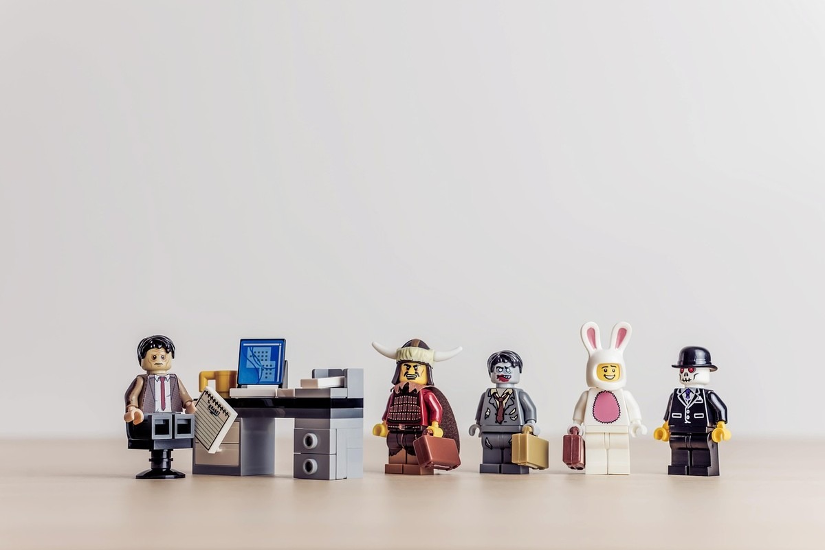 Six figurines Lego sur une table, dont un personnage devant un ordinateur, un viking, un lapin et un homme en costume