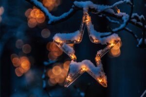 Étoile lumineuse enneigée accrochée à une branche, éclairage doux