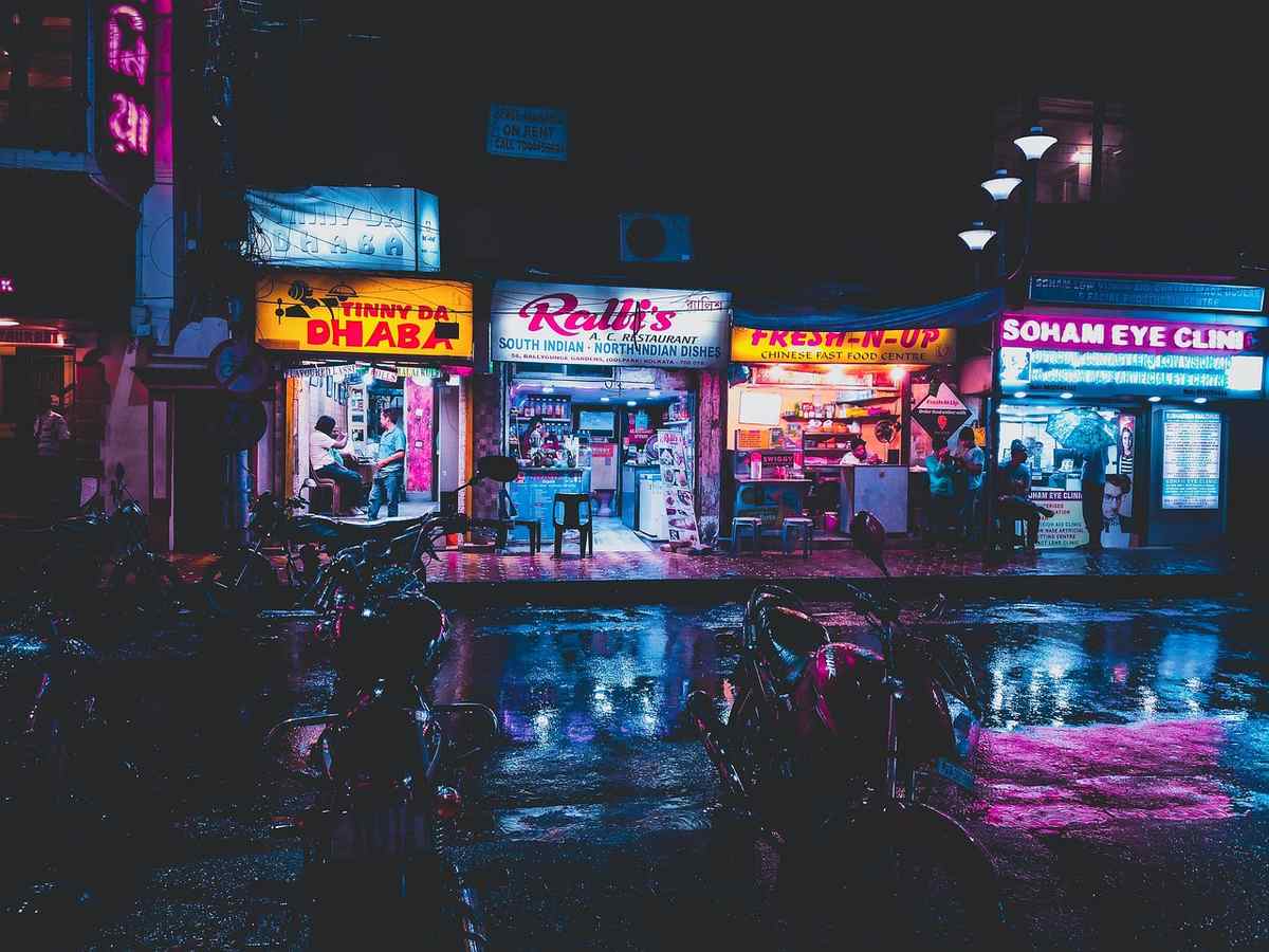 Boutiques éclairées, trottoir mouillé, motos à l'arrêt sous la pluie Boutiques éclairées, trottoir mouillé, motos à l'arrêt sous la pluie
